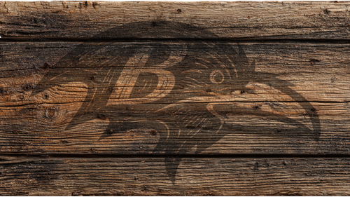 A dark brown graphic of a raven head with a stylized letter B on its wing, printed over a rustic horizontal wood plank background.