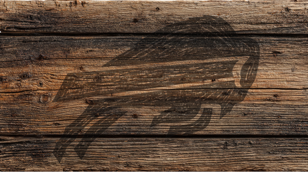 A rustic dark brown wood plank surface with a large black engraved or burned graphic of a bird, likely a hawk or eagle, across the center.