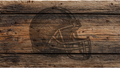 A rustic engraved design of a football helmet on weathered brown wooden planks.